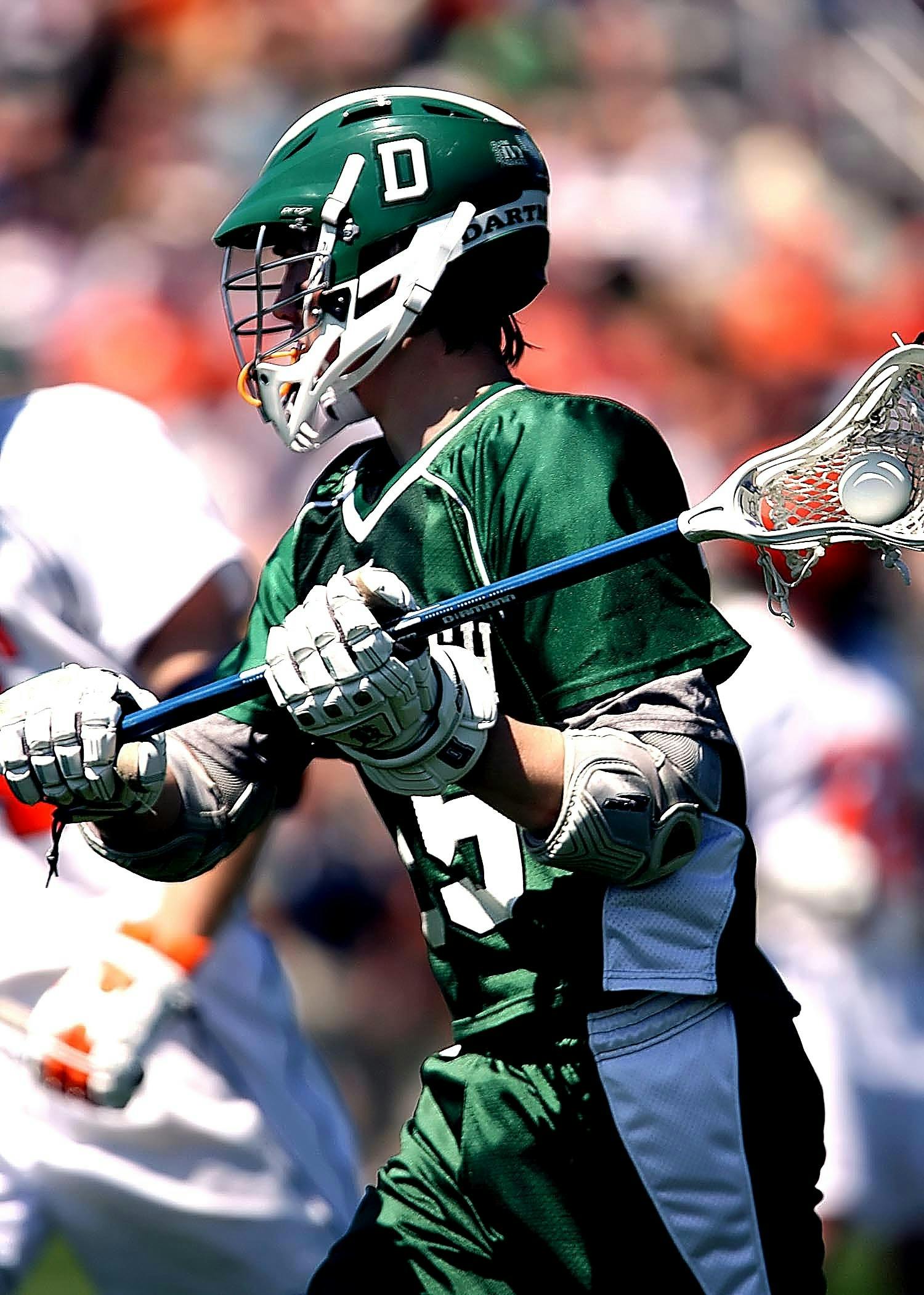 Boys lacrosse player cradling in green uniform